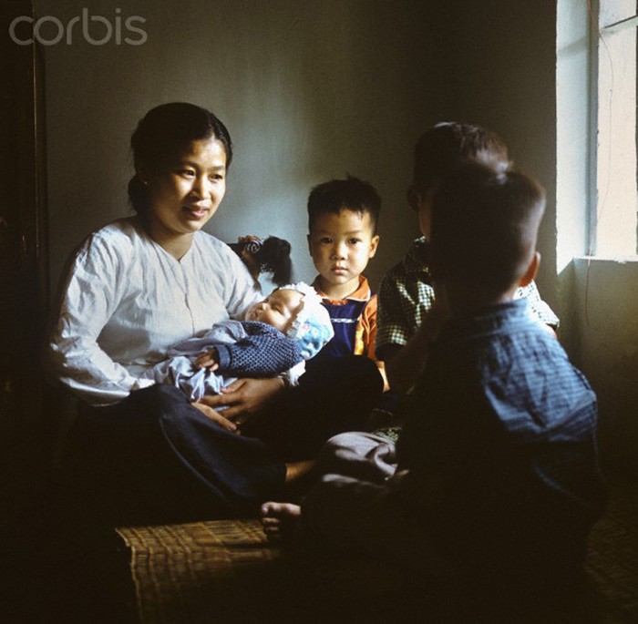 Một phụ nữ trẻ trên tay bế một đứa bé bên cạnh những đứa trẻ khác trong một ngôi nhà ở phố Khâm Thiên. Ảnh.Werner Schulze.